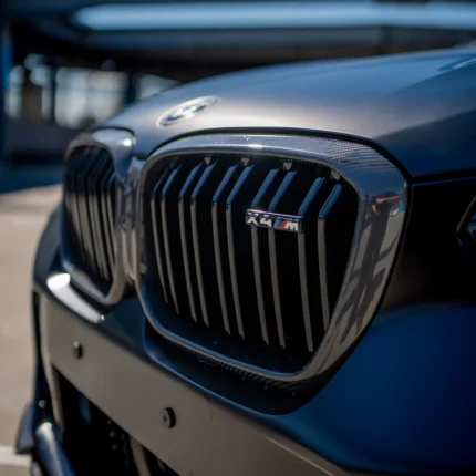 X4M front kidney grille in gloss carbon with M badge detail, emphasizing high-performance styling