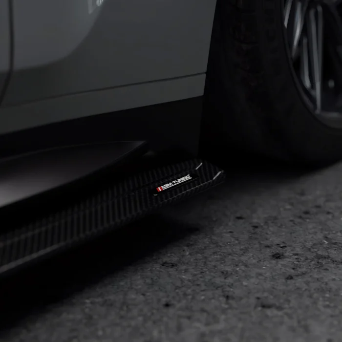 Straight close-up of carbon fibre side skirt running beneath grey BMW M4 G82 door line
