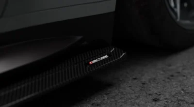 Close-up of ASM Tuning logo embedded on the carbon side skirt edge of BMW M4 G82