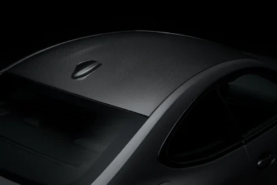 Top-down view of a BMW G82 featuring dry carbon fiber roof panel with a shark fin antenna, highlighting weight-saving design and aerodynamic styling