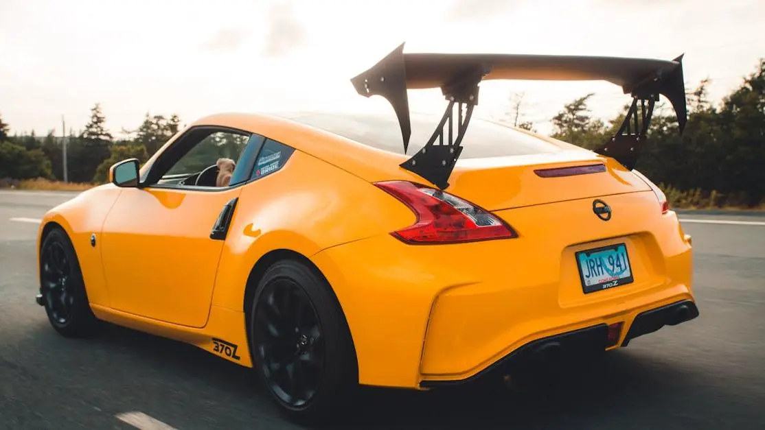 Yellow 370Z sports car with prominent car spoiler driving on highway